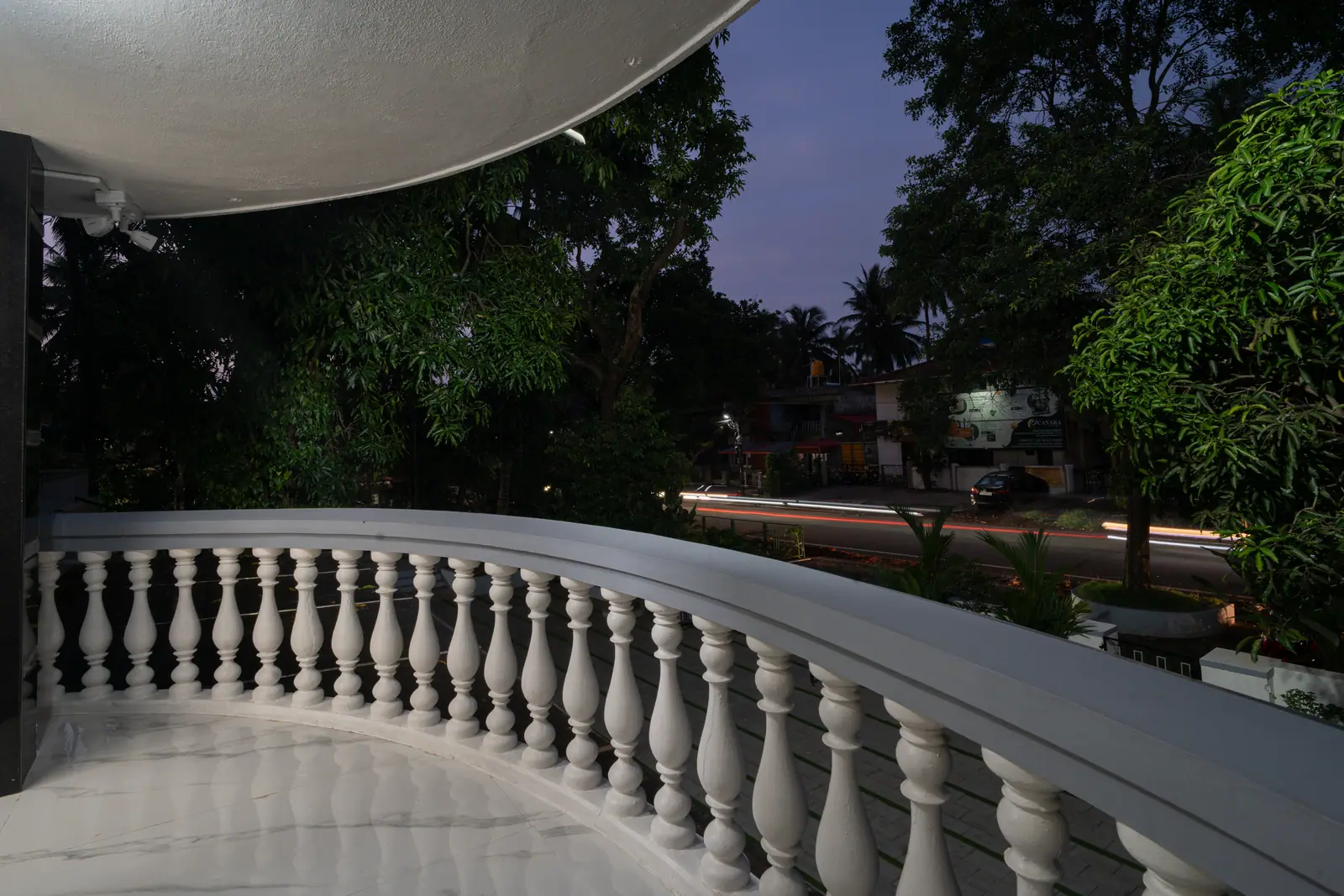 The curved balcony offers a serene vantage point to watch the evening light fade over Udupi.