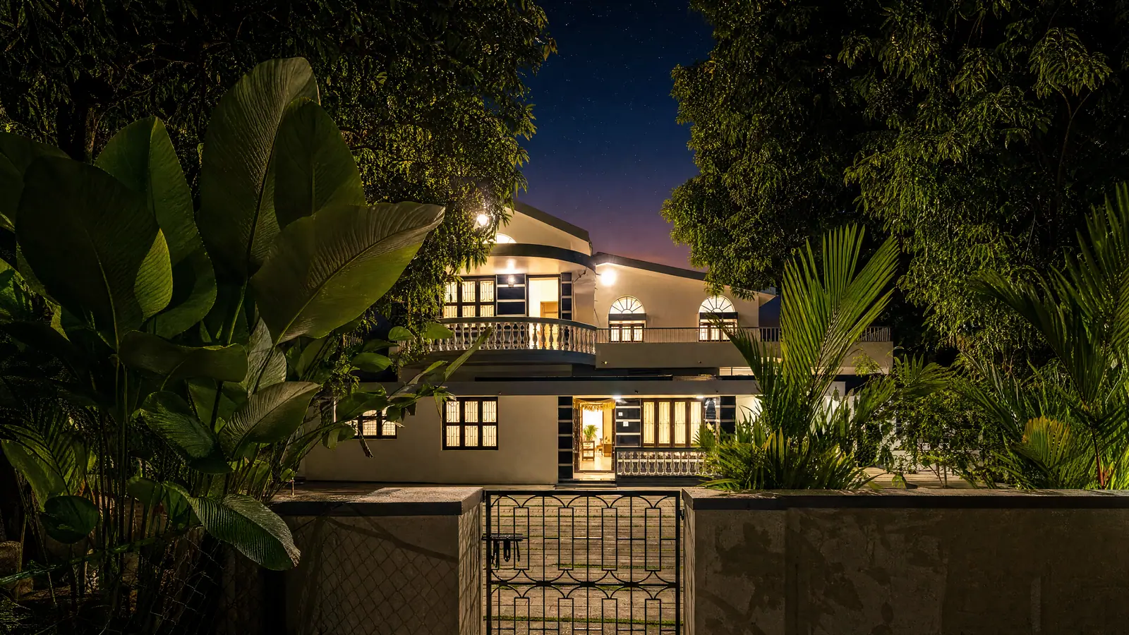 The house glowing warm at dusk, framed by foliage